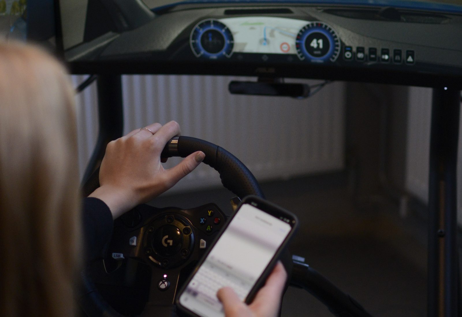 Förare i körsimulator med mobil i handen